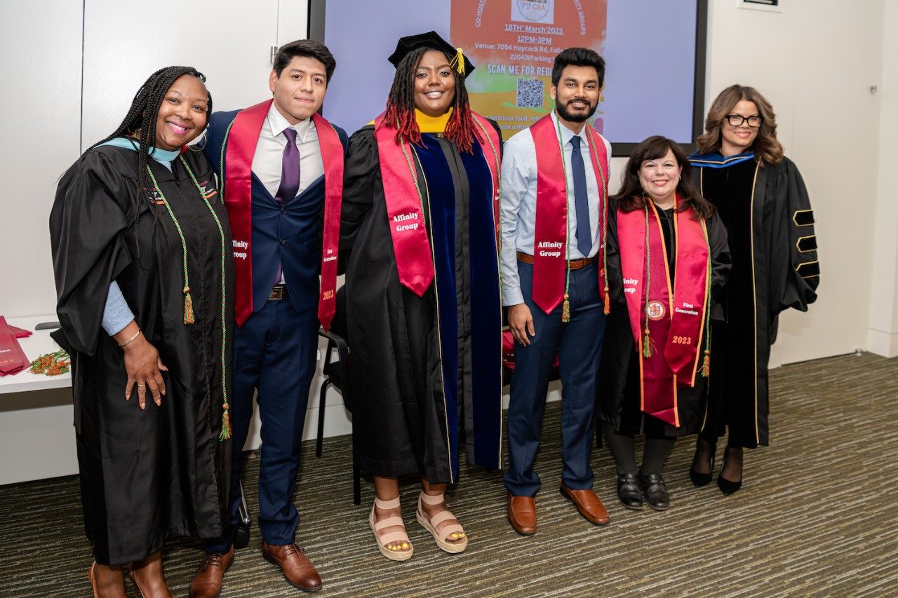 A group of students in Commencement regalia posing with Dr. Chontrese Hayes from the Graduate School